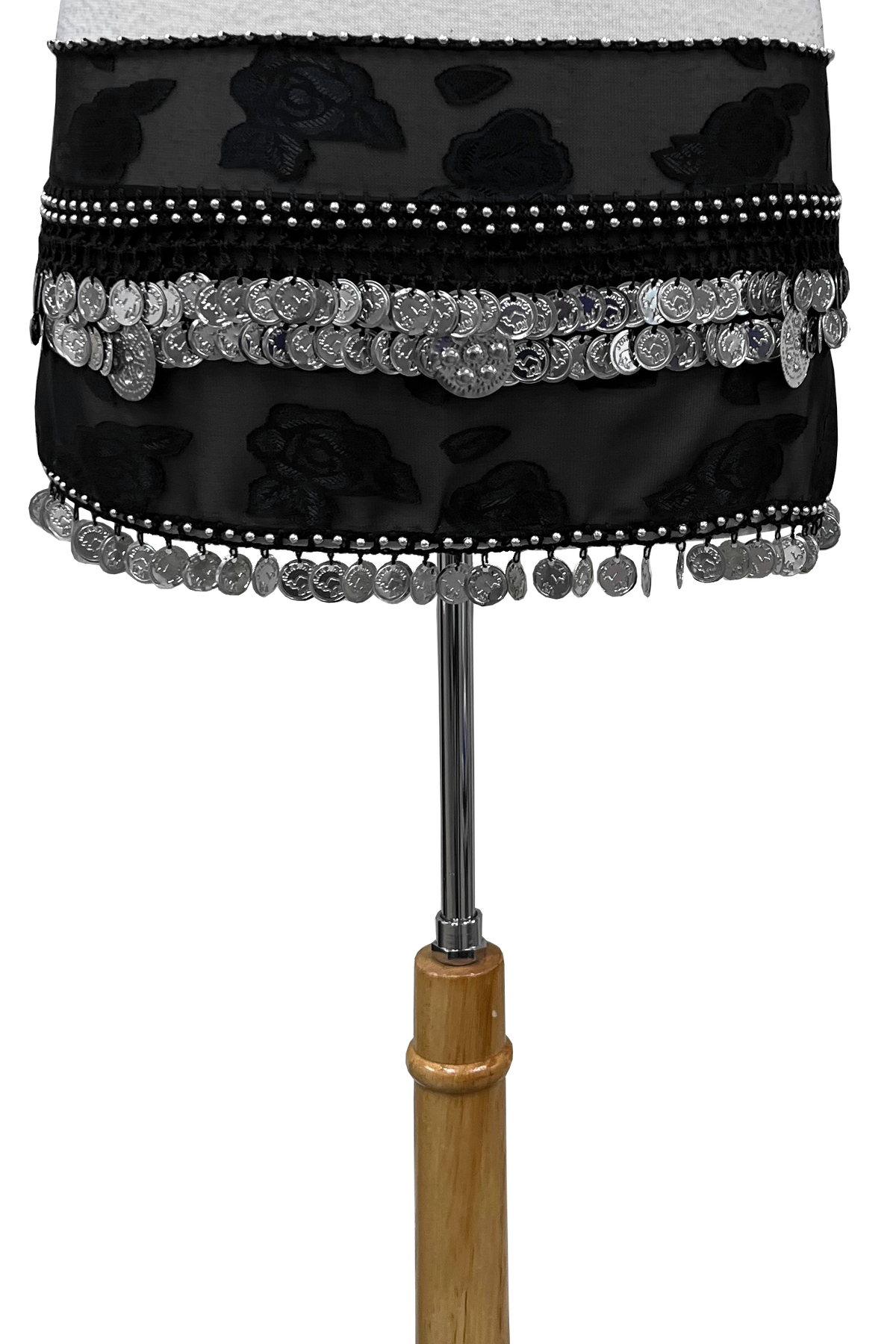 A black fabric hip sash with floral patterns, silver coin fringe, and bead trim, displayed on a dress form stand against a white background.