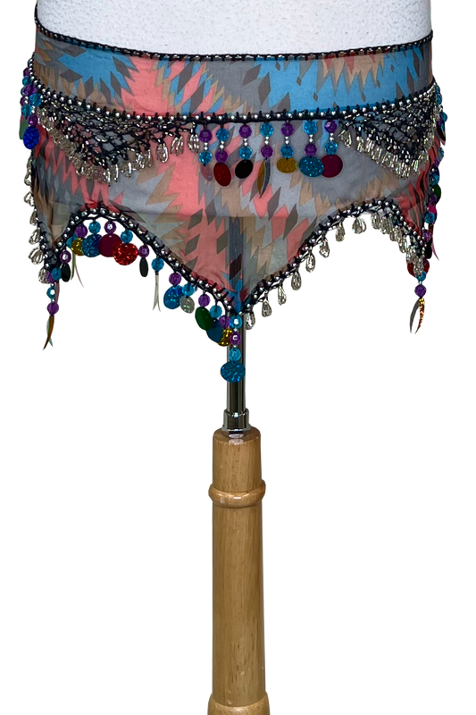 A colorful patterned belly dance hip scarf with silver and multicolor beads, sequins, and fringe, displayed on a mannequin torso against a white background.