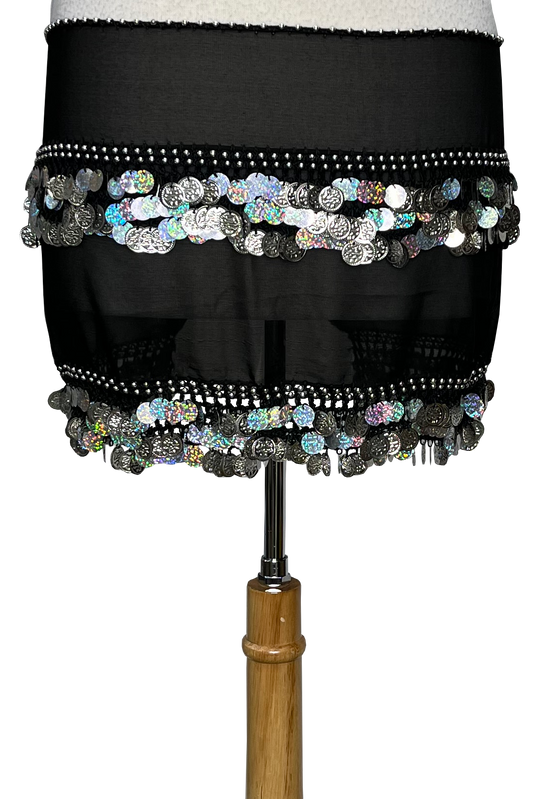 A black sheer hip scarf with silver coin embellishments and holographic sequins, displayed on a dress form against a white background.