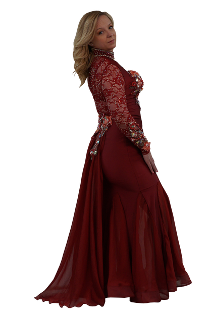 A woman modeling a floor-length burgundy mermaid gown with long sheer lace sleeves, floral work, and a high beaded neckline, shown against a plain white background.