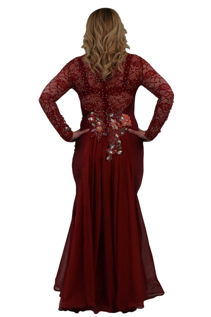 A woman shown from the back wearing a long-sleeve burgundy formal gown with lace detailing, beadwork, and a floral embellishment at the waist, set against a plain white background.