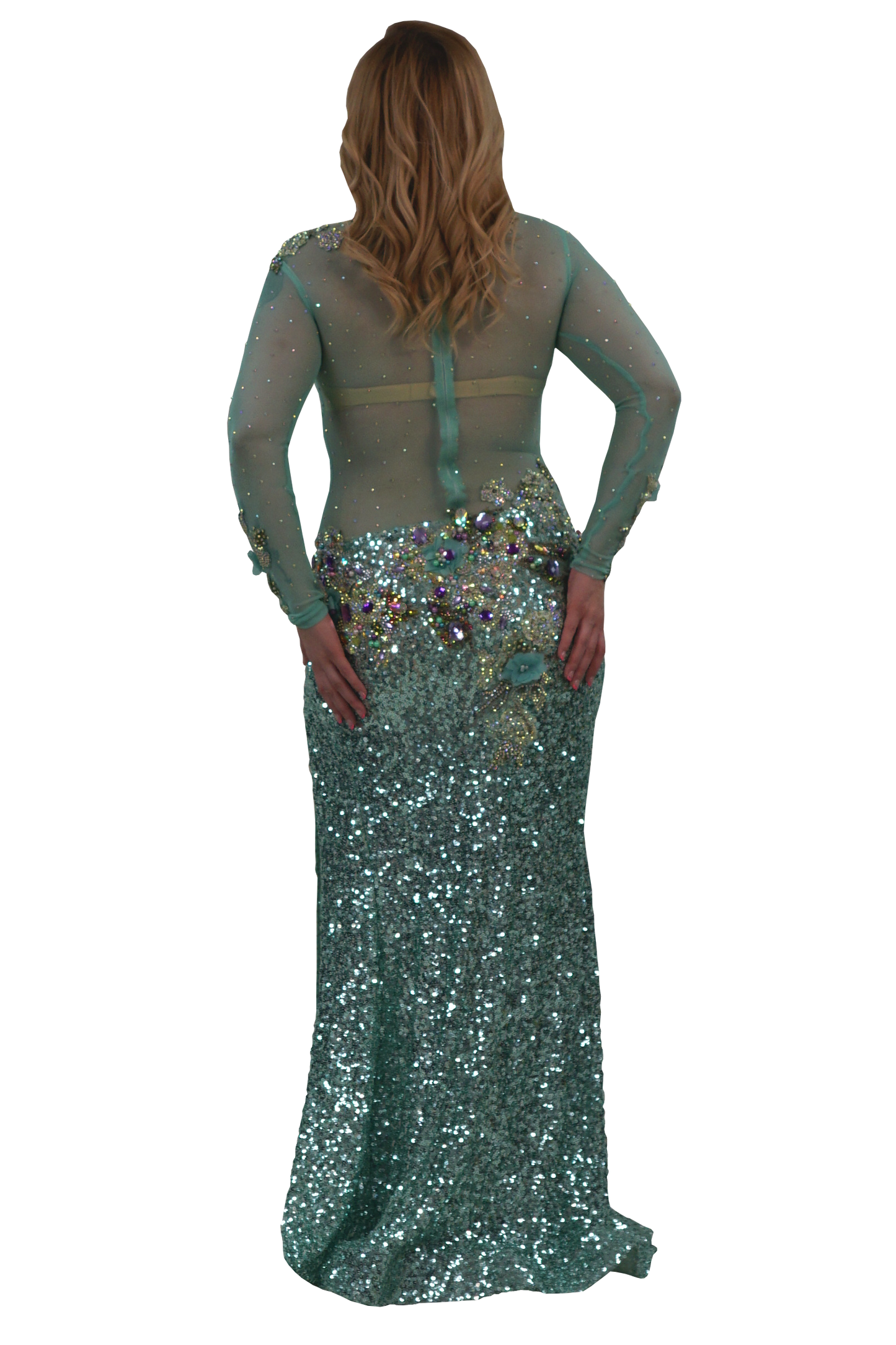 A woman modeling a floor-length teal sequined gown from the back, featuring sheer long sleeves, a structured back with a central strap, and a heavily embellished waistband with iridescent sequins and rhinestones, set against a plain white background.