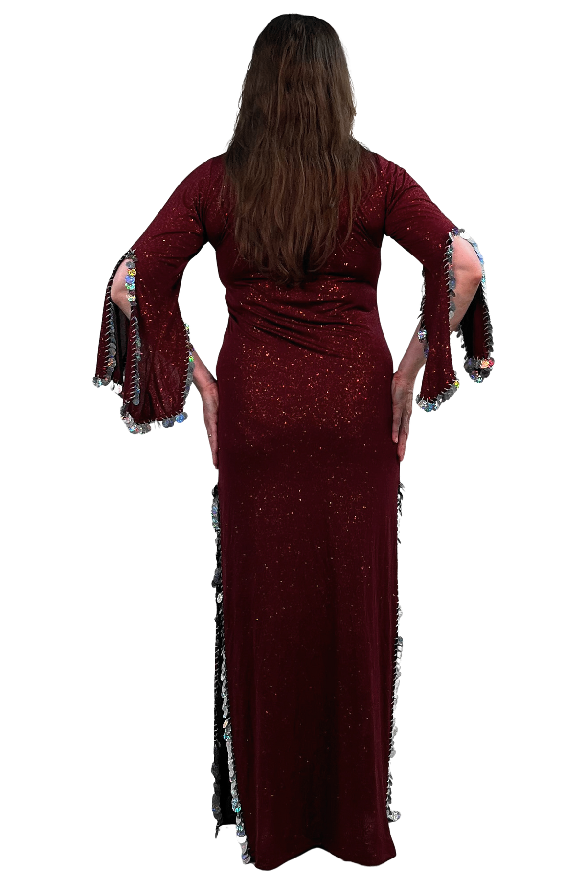 A woman viewed from the back wearing a long burgundy sequined maxi dress with fringed bell sleeves and side slits, set against a plain white background.