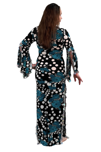 A woman modeling a long black maxi dress with teal floral patterns and white polka dots, shown from the back against a plain white background.
