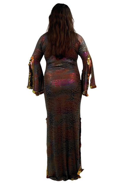 A woman viewed from the back wearing a floor-length, fitted dress with long flared sleeves. The dress has an iridescent, metallic pattern in dark brown, bronze, purple, and gold tones.