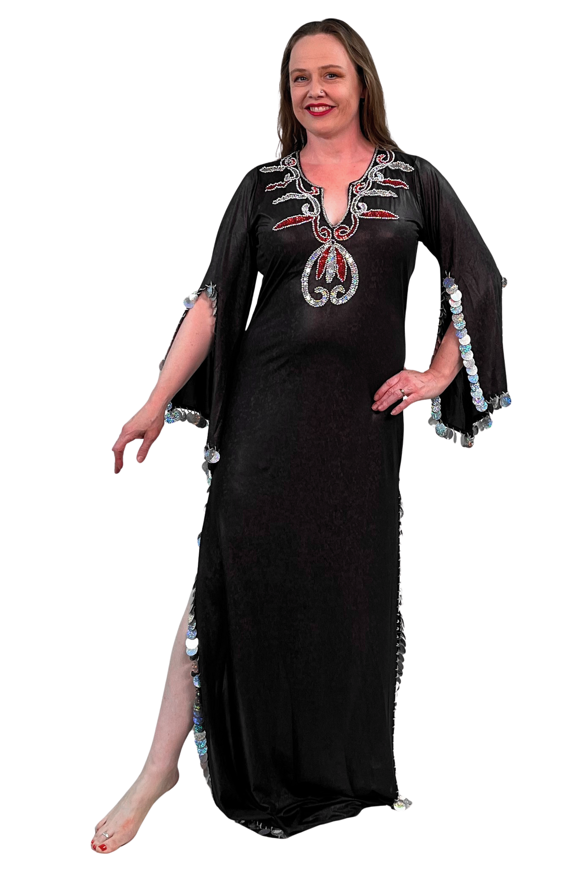 A woman modeling a brown maxi dress with silver and red sequin details on the neckline and silver sequined trim on the sleeves and side slit, set against a plain white background.