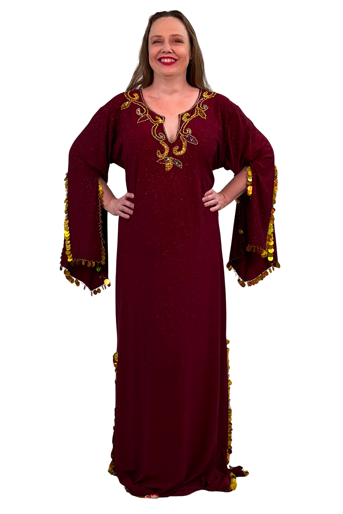 A woman modeling a long burgundy maxi dress with gold sequins and paillette trim on the sleeves and hem, set against a plain white background.