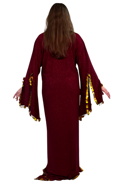 A woman viewed from behind wearing a long burgundy maxi dress with wide bell sleeves trimmed in gold paillettes, set against a plain white background.