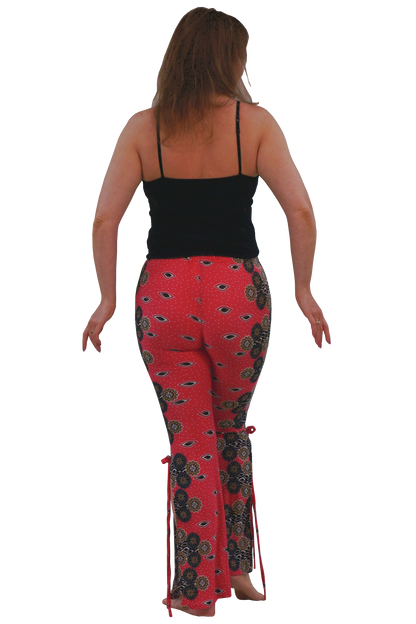 A woman shown from behind wearing pink patterned flared pants with black and dark brown paisley-style motifs, a black camisole top, and bare feet against a plain white background.