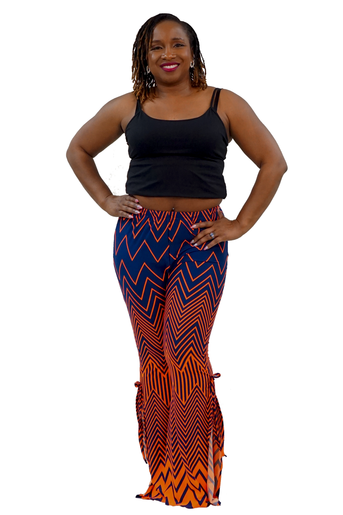 A woman modeling a black tank top and high-waisted flared pants with a bold blue, orange, and black zigzag pattern, set against a plain white background.