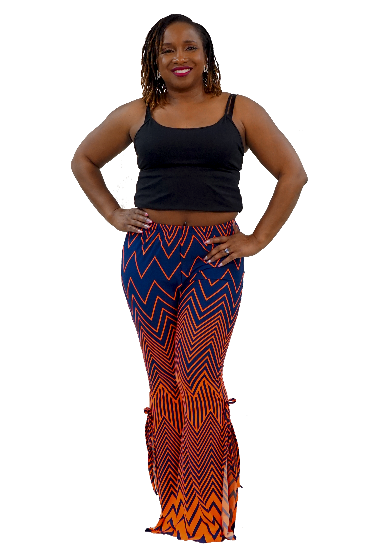 A woman modeling a black tank top and high-waisted flared pants with a bold blue, orange, and black zigzag pattern, set against a plain white background.
