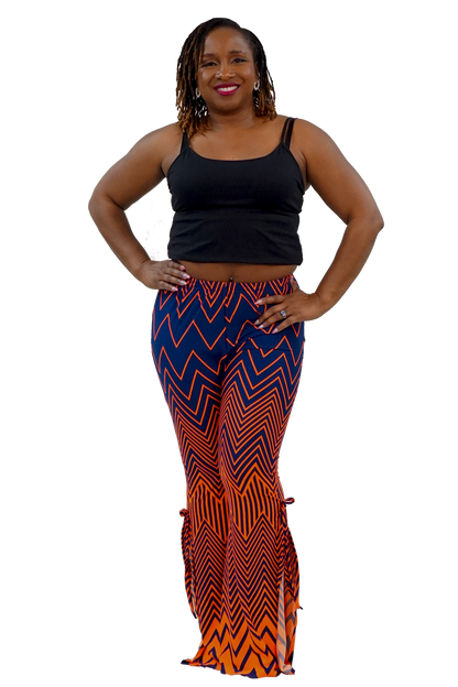 A woman modeling a black tank top and high-waisted flared pants with a bold blue, orange, and black zigzag pattern, set against a plain white background.