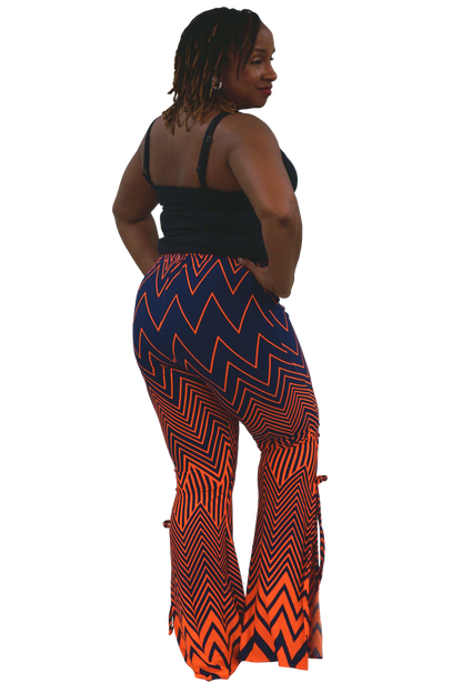 A woman shown from the back wearing a black camisole top and high-waisted, wide-leg flare pants with a bold orange and navy blue chevron pattern, set against a plain white background.