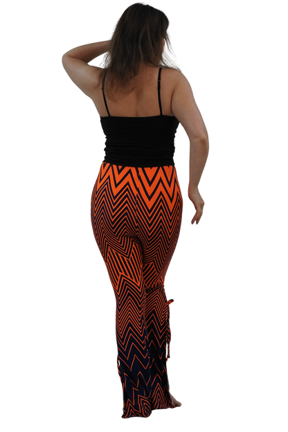 A woman shown from the back wearing a black spaghetti-strap top and high-waisted, flared leggings with a bold orange and black chevron pattern, set against a solid white background.