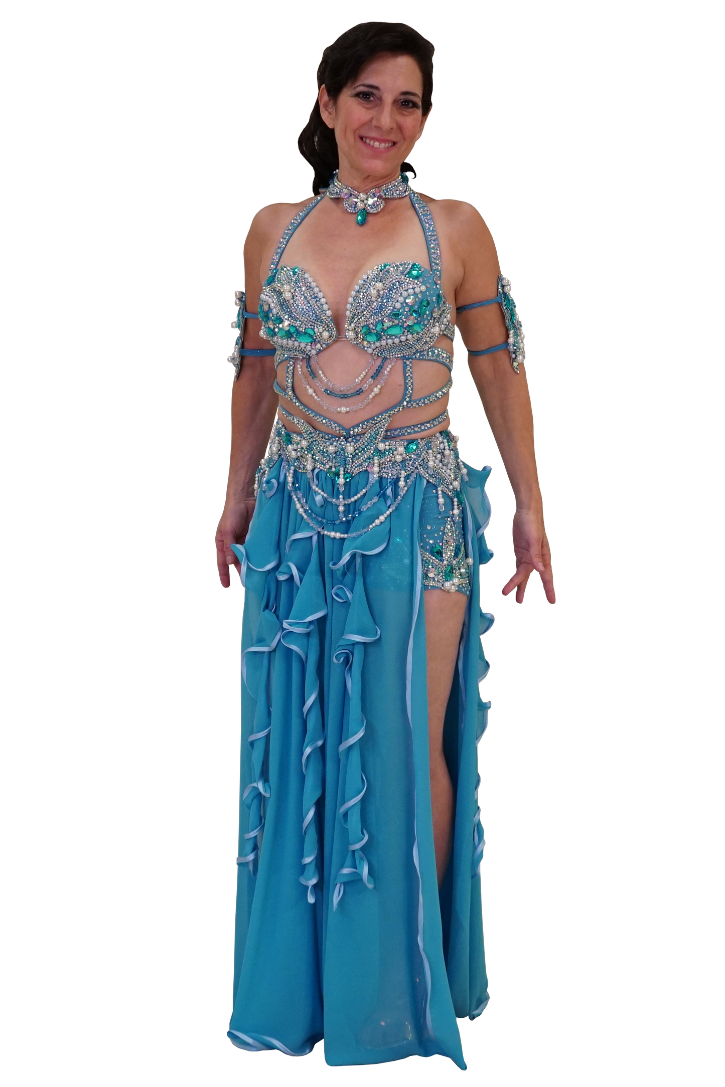 A woman modeling a turquoise and silver belly dance costume with a matching embellished bra top, hip scarf, arm bands, and a long ruffled skirt on a plain white background.