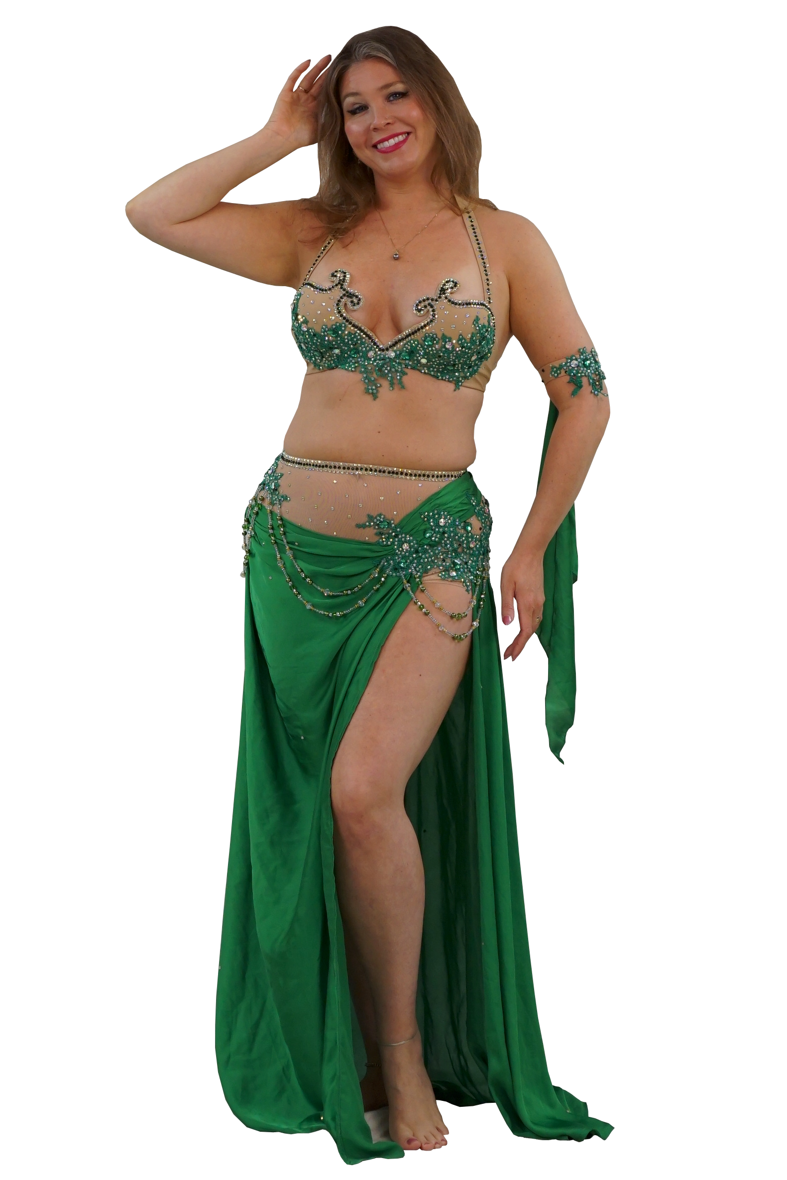 A woman modeling a green belly dance costume with an embellished bra top, matching arm piece, and a long draped skirt with a high leg slit, shown against a plain white background.