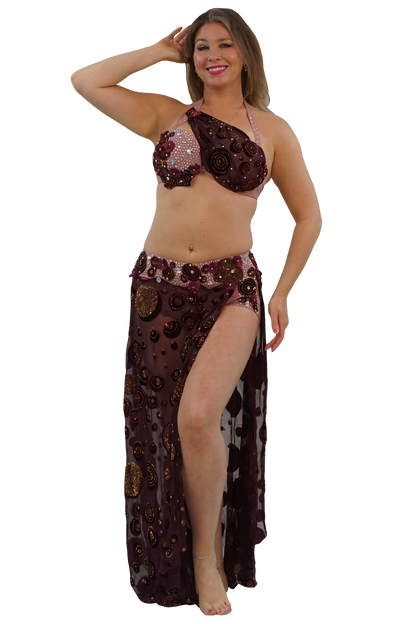 A woman modeling a two-piece belly dance costume consisting of a one-shoulder halter bra top and a matching sheer skirt with sequined circular patterns, set against a plain white background.
