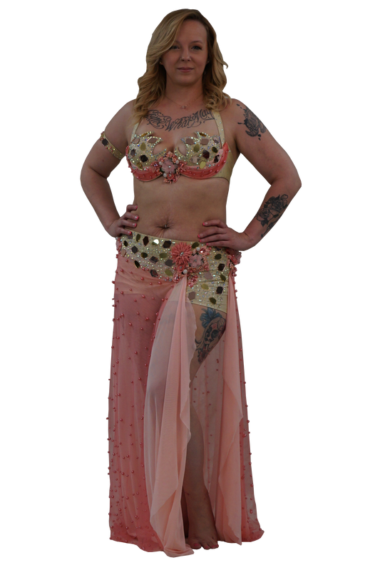 A woman modeling a belly dance costume consisting of a gold and pink embellished bra top, a matching sheer pink skirt, and  gold sequined shorts, set against a plain white background.
