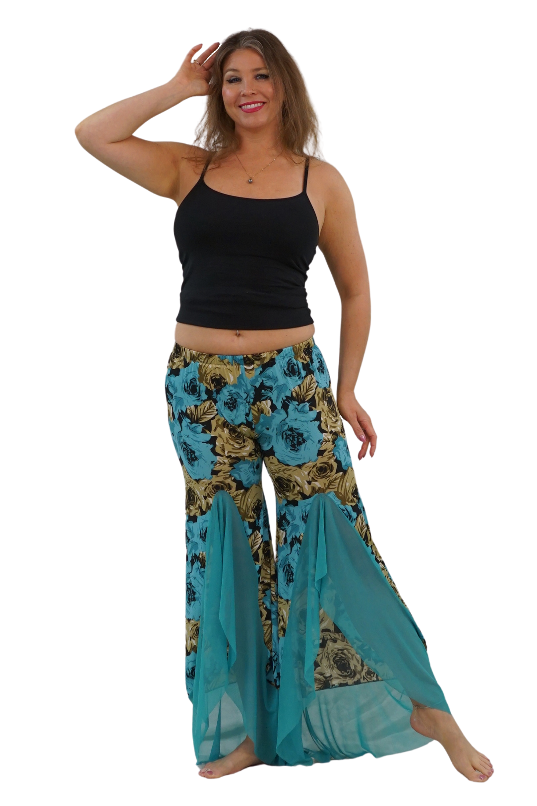 A woman modeling a pair of wide-leg bohemian-style pants with a teal, gold, and black floral print, paired with a black tank top, against a solid white background.
