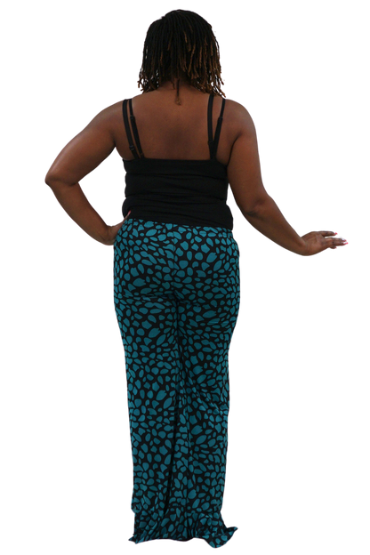 A woman shown from the back wearing a black spaghetti-strap top and teal pants with a black abstract spotted pattern, isolated on a white background.